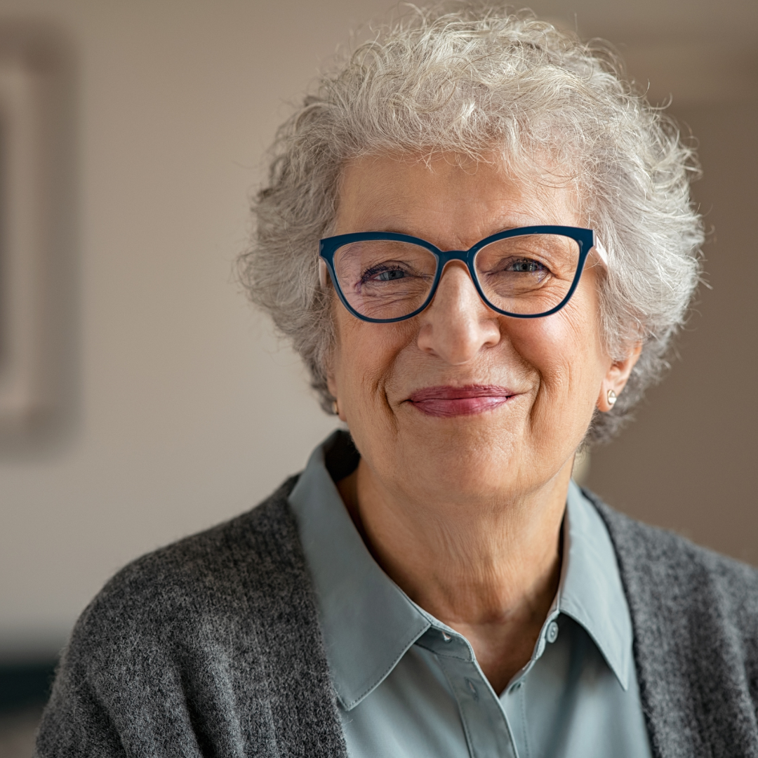 smiling woman with grey hair and black glasses