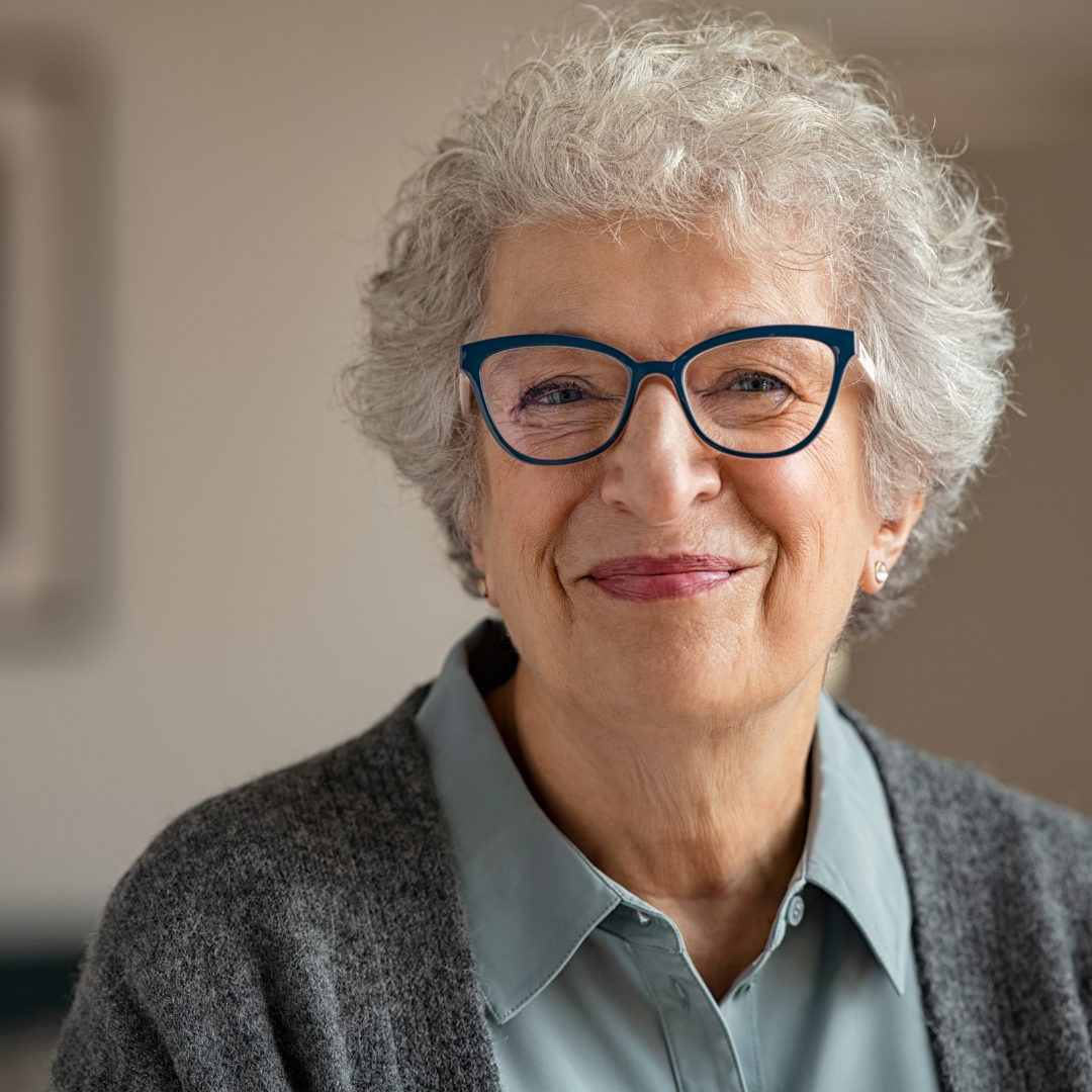 woman with grey hair and glasses smiles at the camera