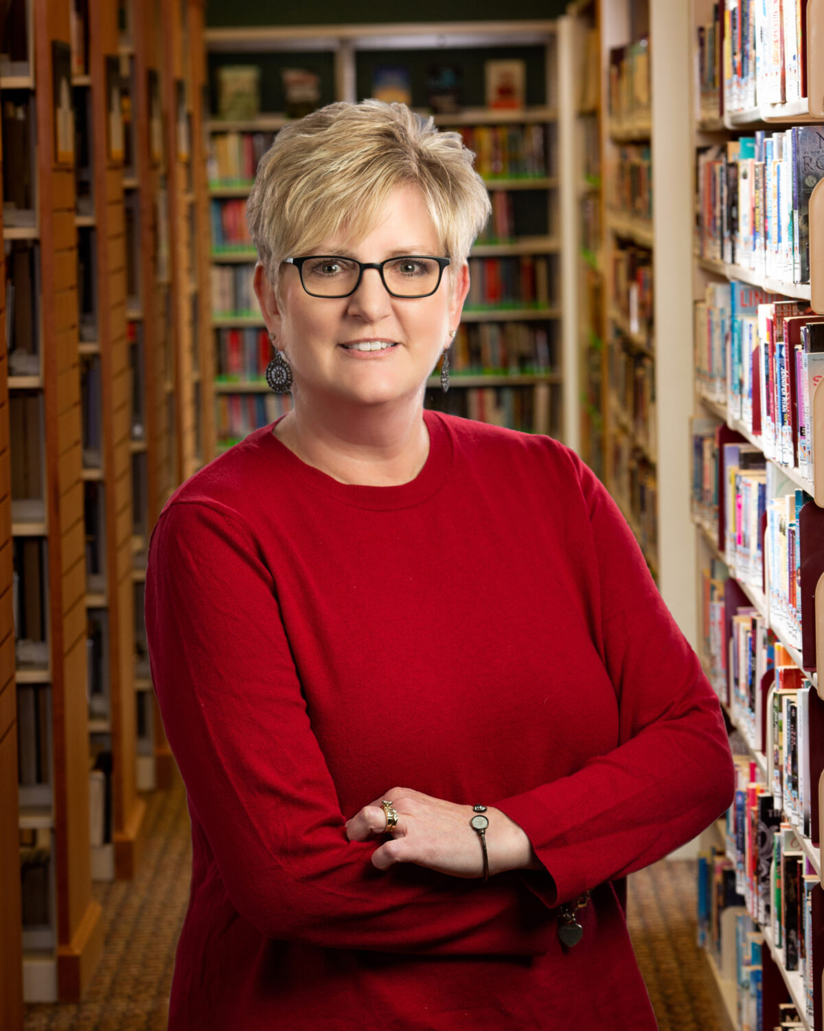 Woman in red shirt and glasses, arms crossed