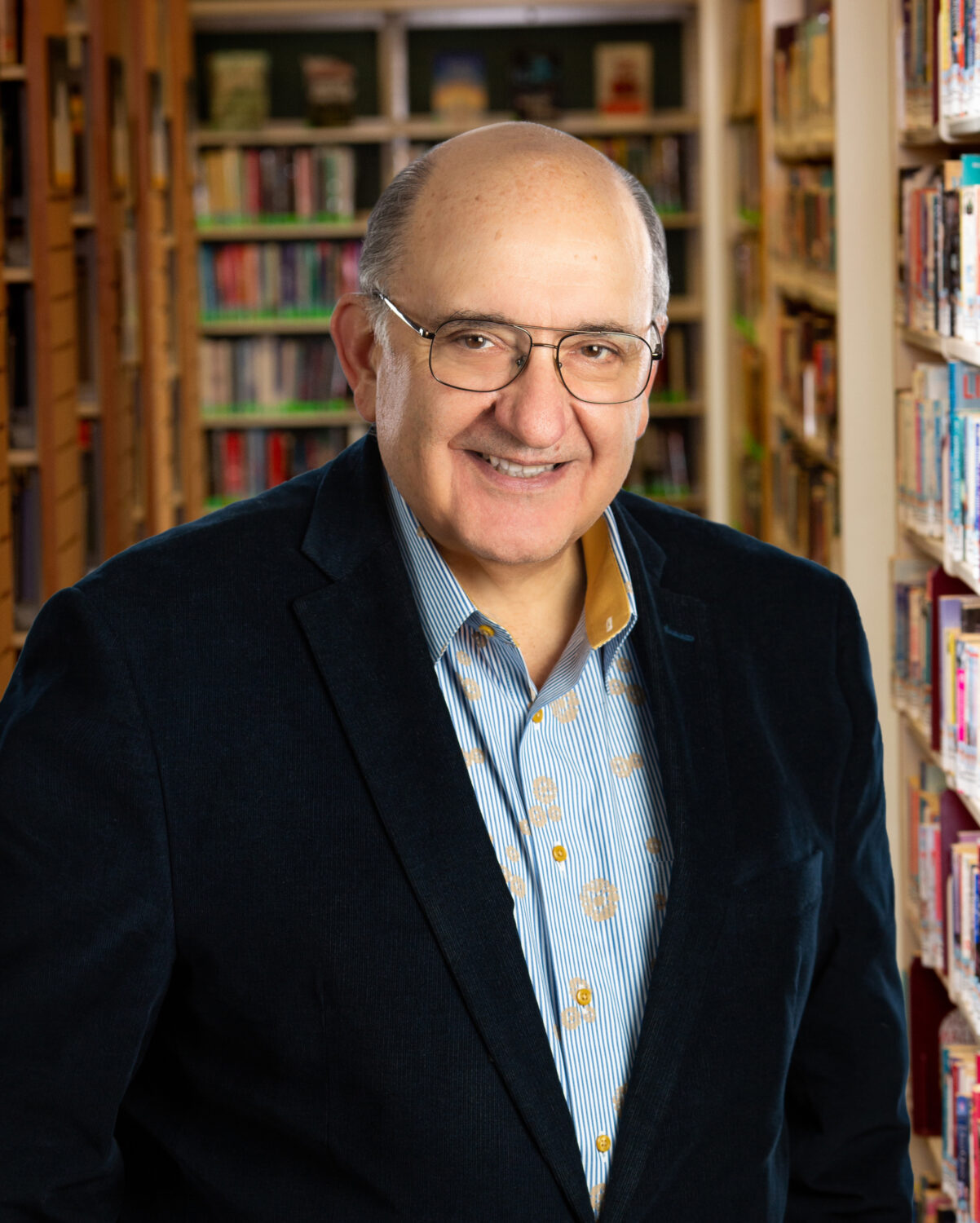 Image of a man wearing a suit coat in front of book shelves