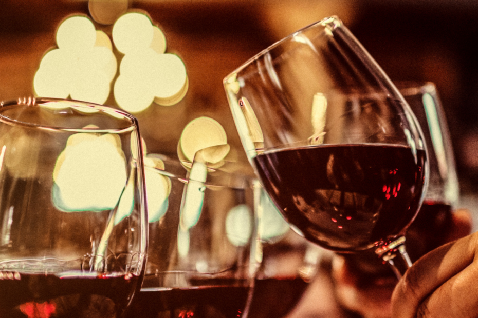wine glasses lifted in "cheers" with moody lighting behind