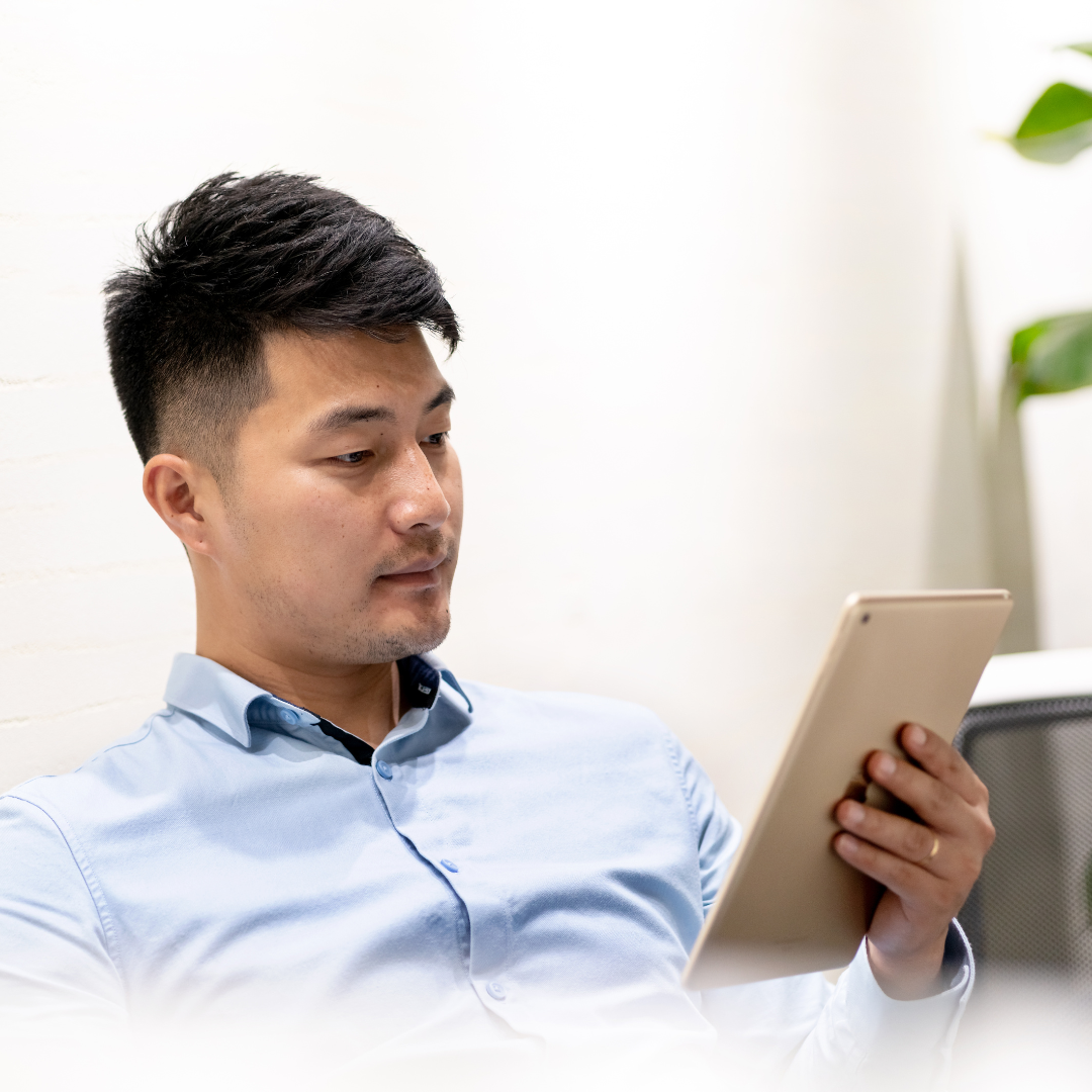 young man looks at a tablet while sitting back