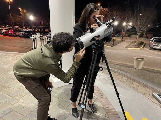 Library employees look through telescope