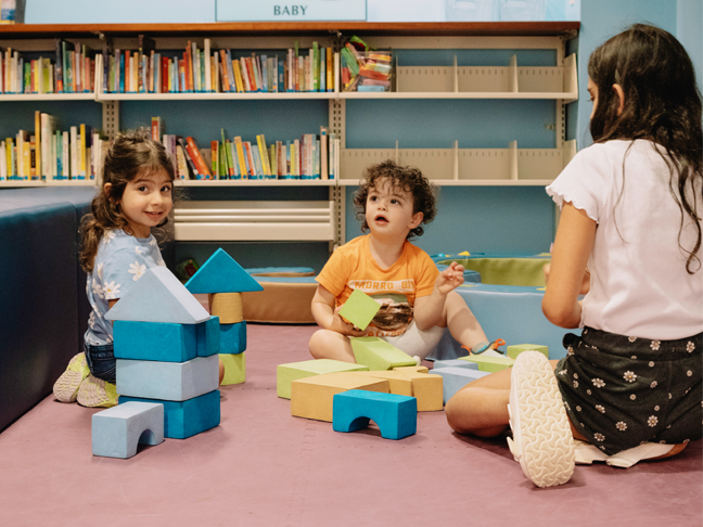 young children play blocks in the library's baby play area