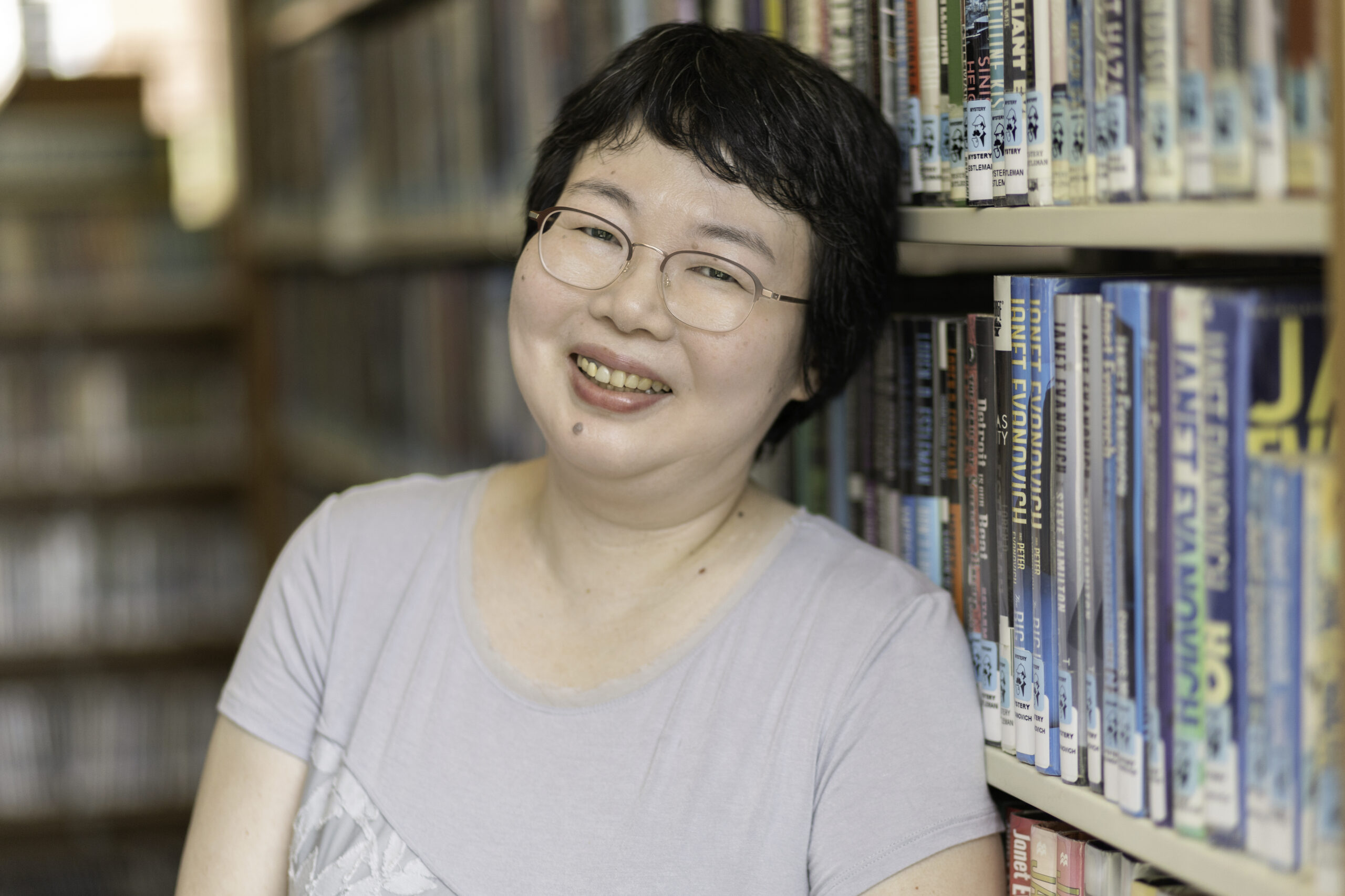 smiling woman in front of a bookshelf