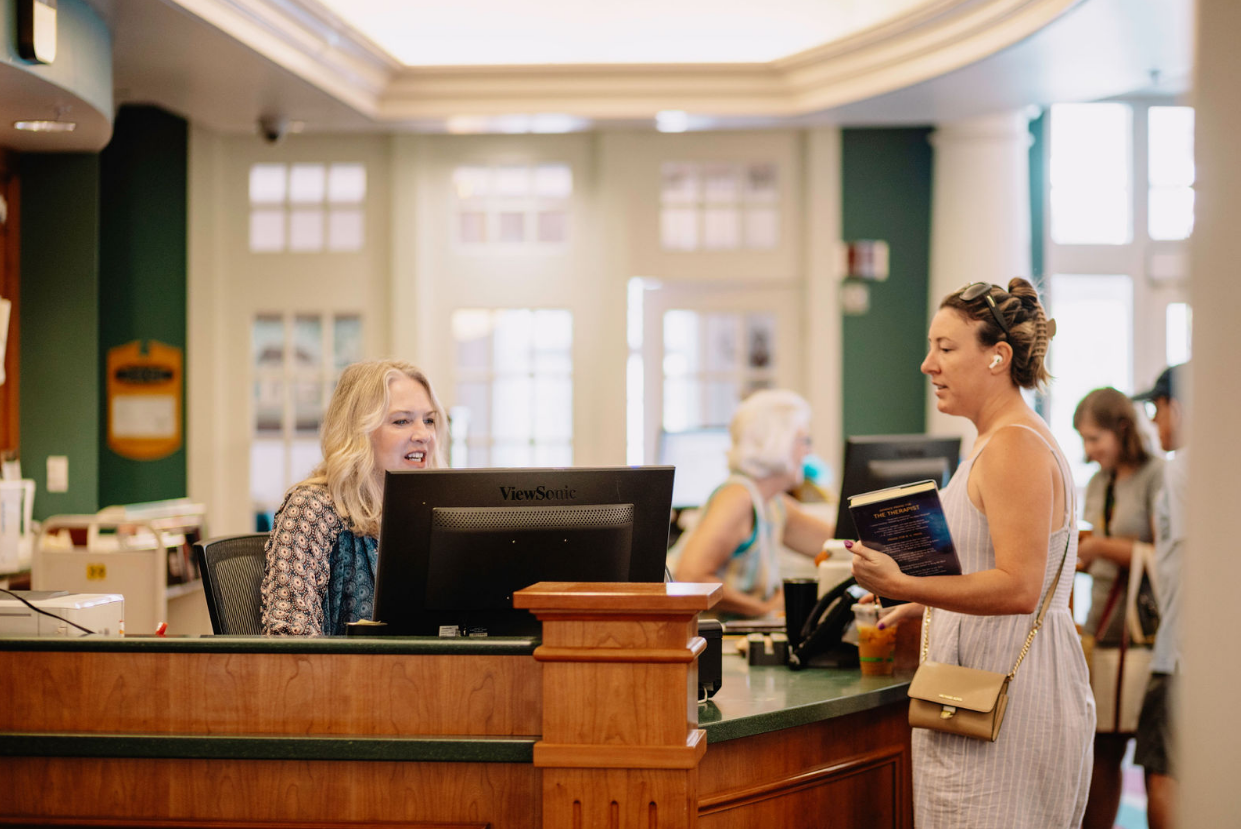 friendly staff member helps a patron check out a book at the circulation desk