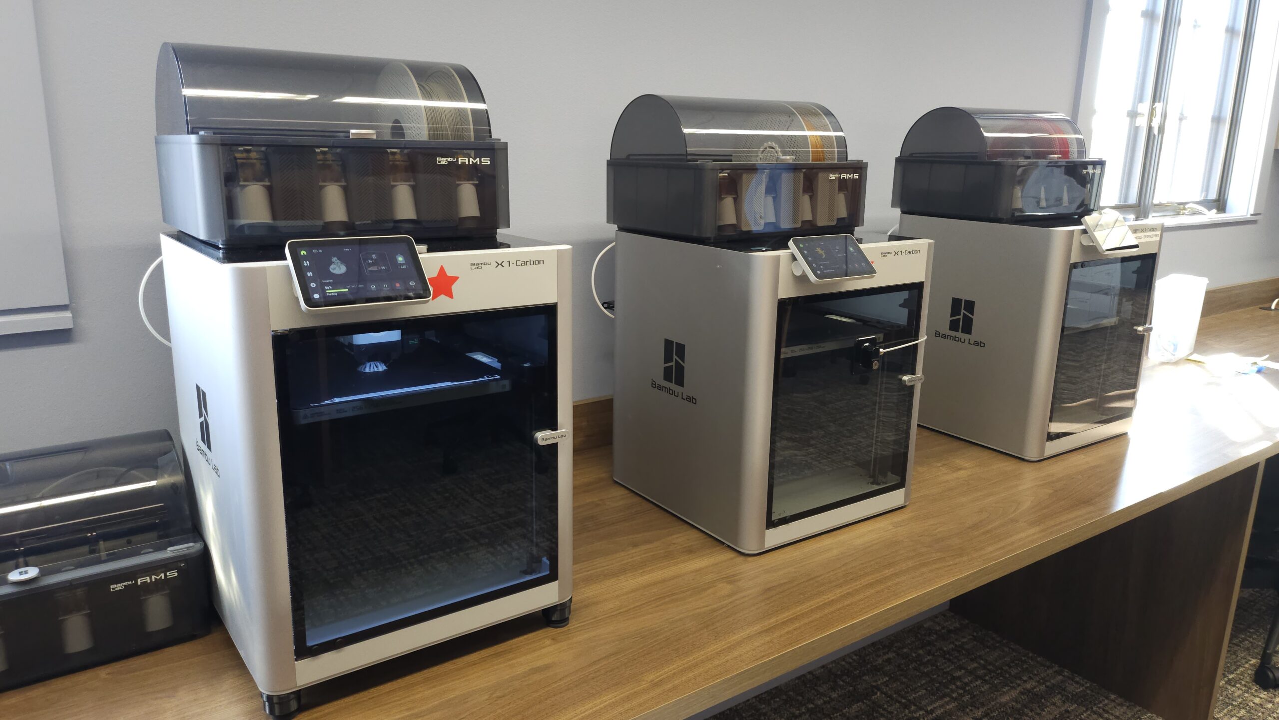 three 3d printers on a wooden desktop