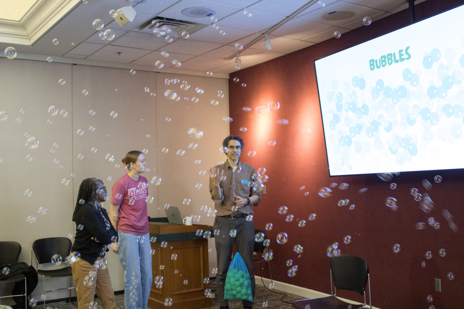 Volunteers Toni and Emily debrief with Brad, surrounded by bubbles.