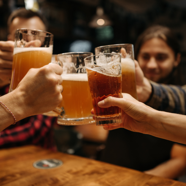 hands holding up glasses of beer to cheers